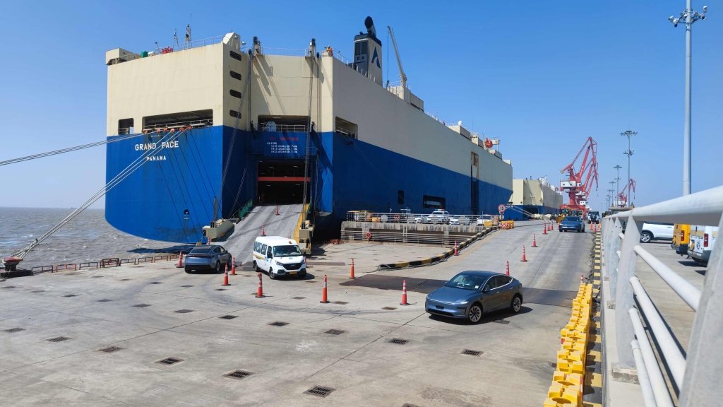 Shanghai-built Tesla Model Y vehicles beside a roll-on roll-off export ship