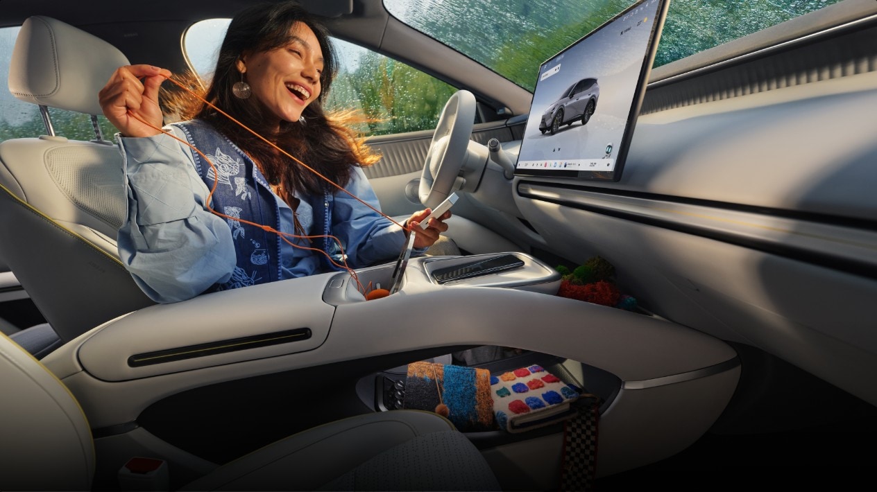 XPeng promotional cabin image showing a front-seat occupant beside the MONA L05 central screen and floating console